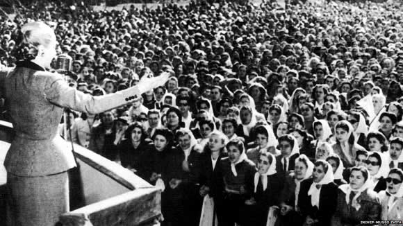 Black & white photo of Evita addressing the crowd from the balcony of the Casa Rosada