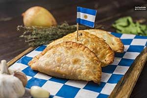 Three empanadas with a little Argentine flag sticking out of the middle 
