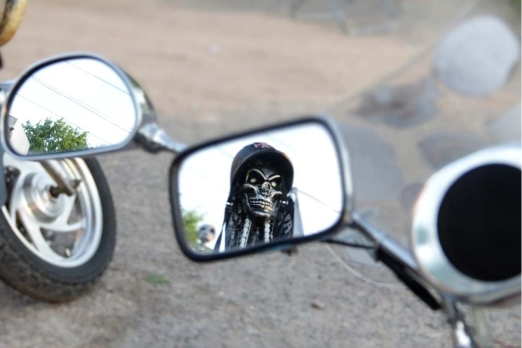 Rearview mirror of a motorcycle that reflects the Angel of Death. 